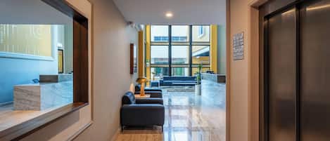 A modern lobby with a reception desk, seating area, and a view of the building's exterior.