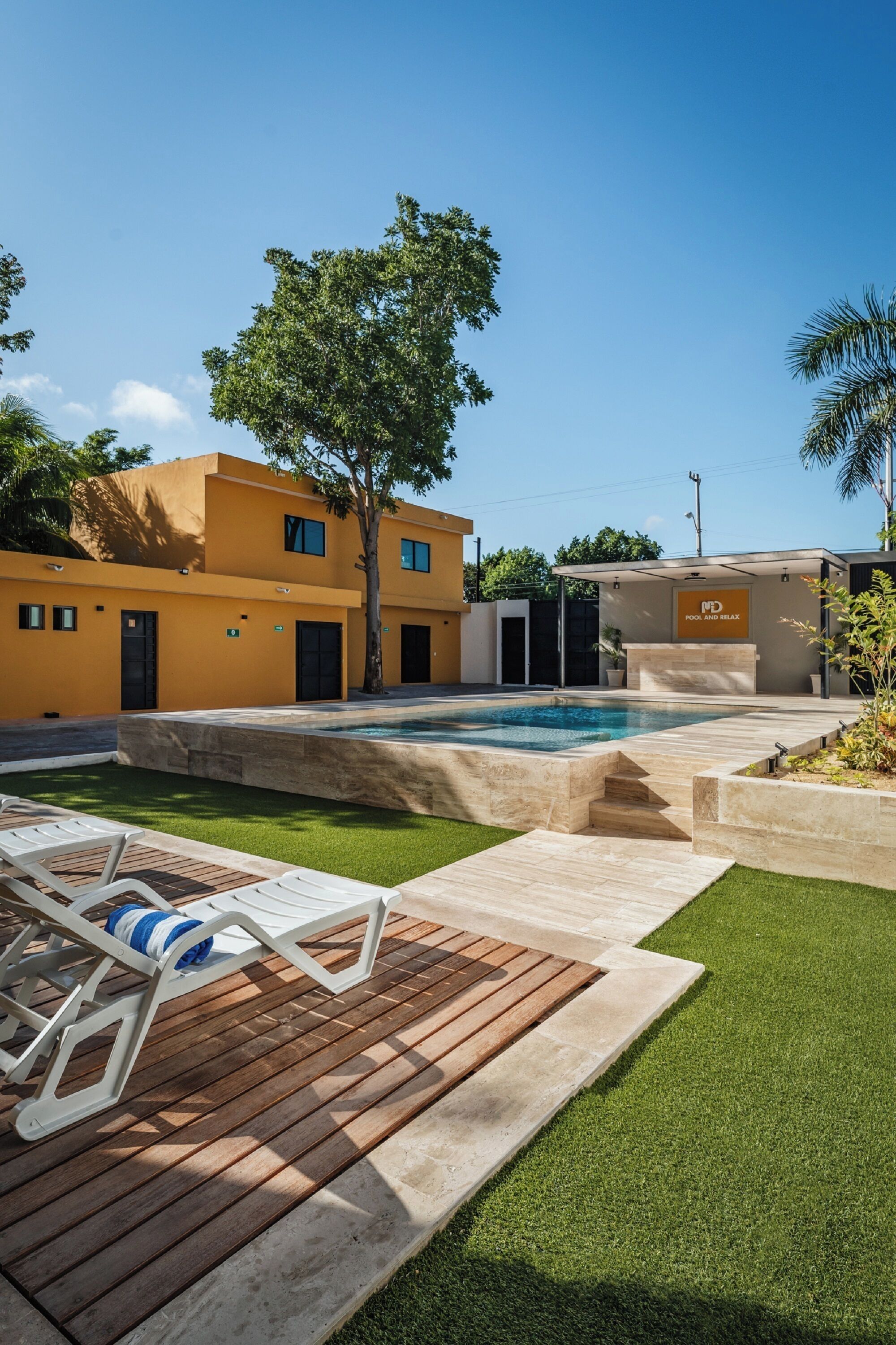 A modern building with a swimming pool, a wooden deck, and a sign that reads "POOL AND BATHROOM".