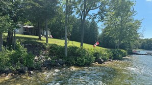 Propiedad frente al lago con una casa, un muelle y una bandera.