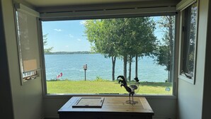Una habitación con un gran ventanal con vistas a un lago, una mesa de madera y una escultura de pájaro.