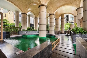 Relax by the pool surrounded by columns and lush greenery.