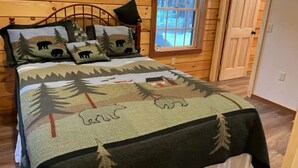 Een slaapkamer in een houten chalet, met een bed, een raam en een deur.