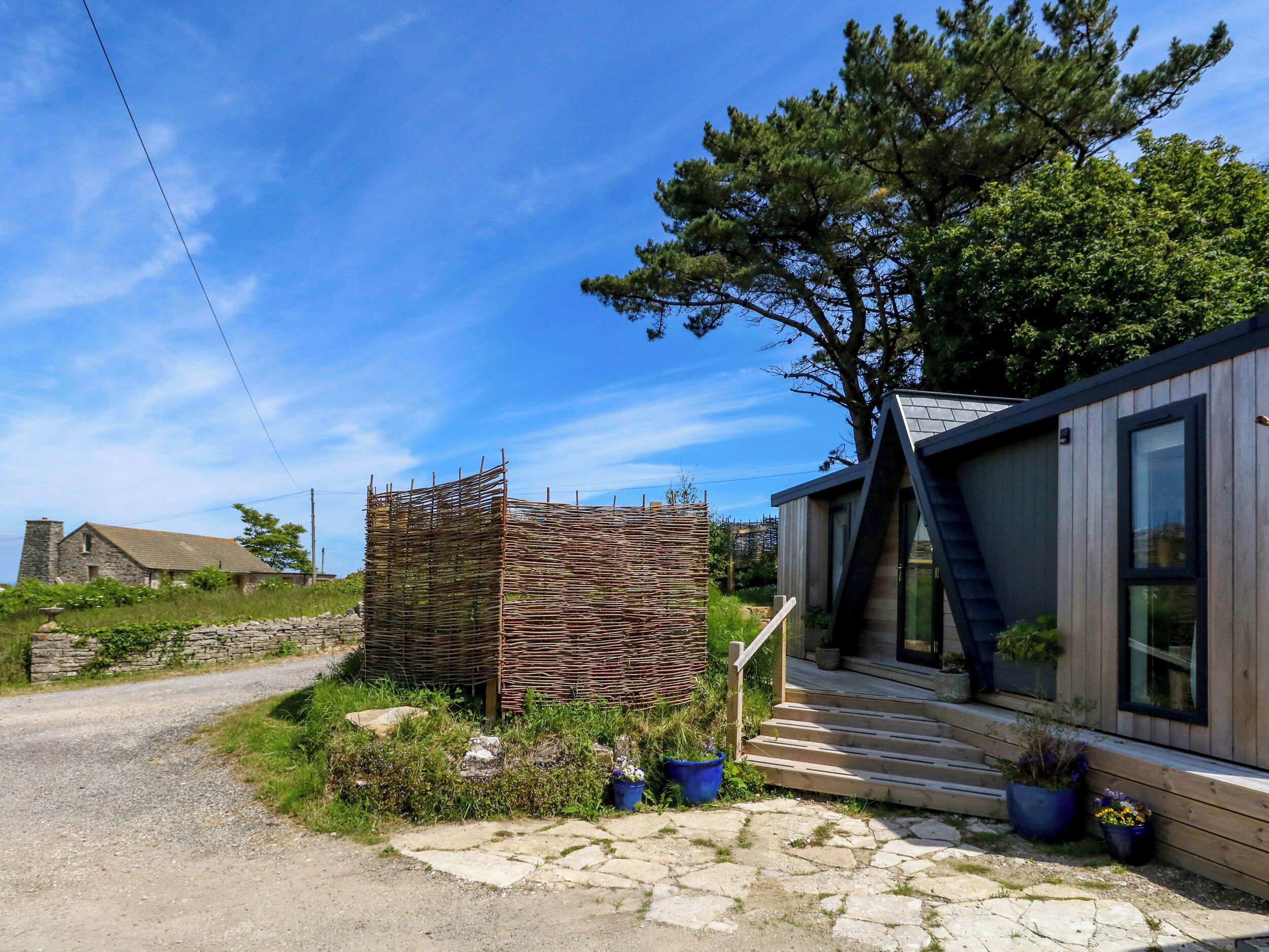 A modern house with a stone wall, a wooden fence, and a tree.