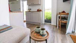 Una cocina moderna con armarios y una ventana, un comedor con una mesa y sillas, y una sala de estar con un sofá y una bandeja de tazas.