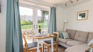 Una sala acogedora con comedor, un sofá y una mesa lista para dos personas.