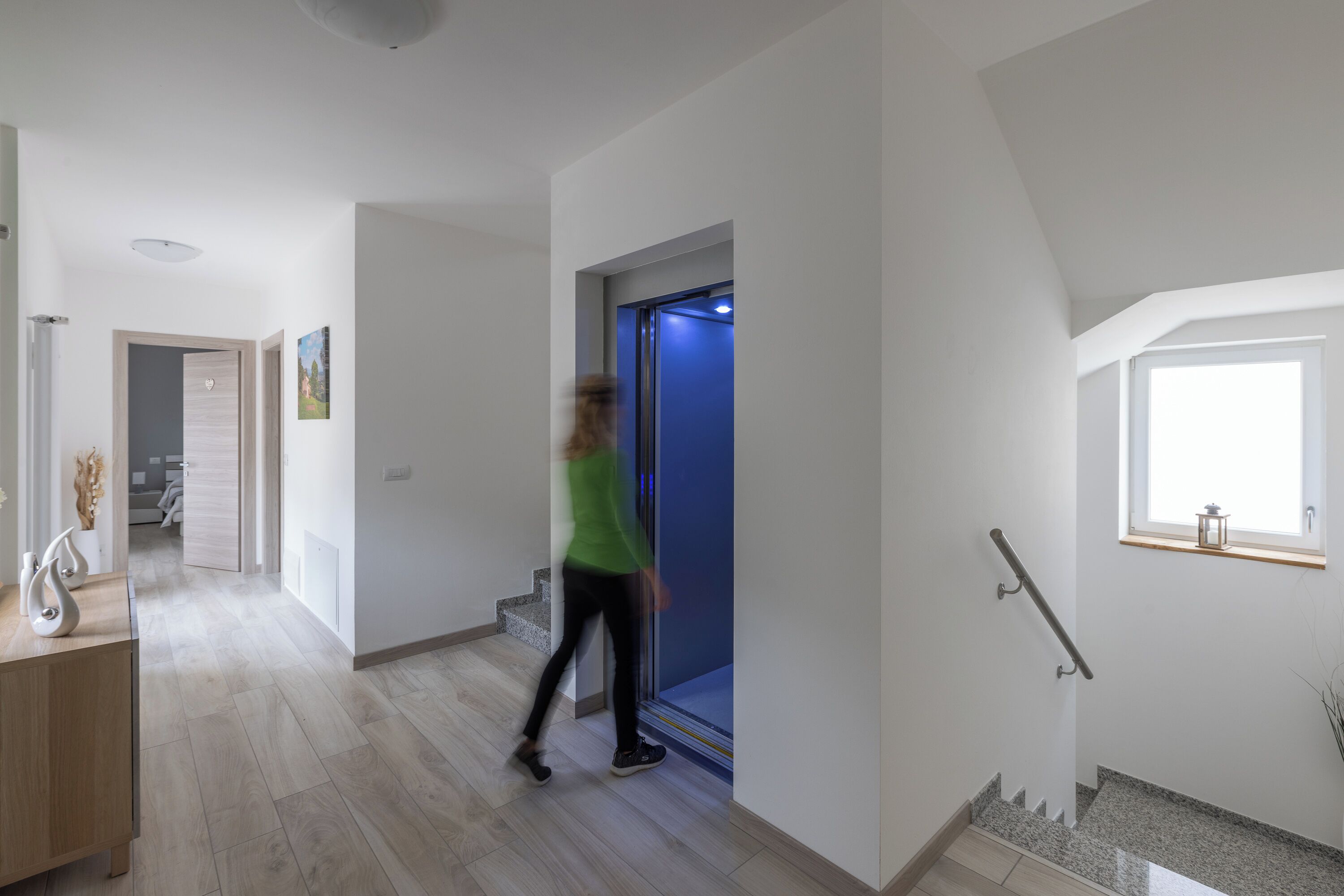 Um interior moderno com uma escadaria, um corredor e uma porta que dá para um quarto.