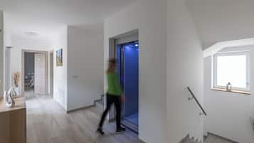 Um interior moderno com uma escadaria, um corredor e uma porta que dá para um quarto.