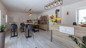 A modern kitchen with a wooden countertop, bar stools, and a welcome sign. - Vigna degli Angeli (Ragogna)