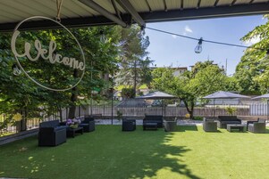 Un patio al aire libre con un letrero de bienvenida, mobiliario exterior y sombrillas.