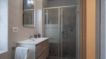 Une salle de bain moderne avec une douche à parois de verre, un meuble-lavabo avec un miroir et une serviette suspendue à un porte-serviettes.