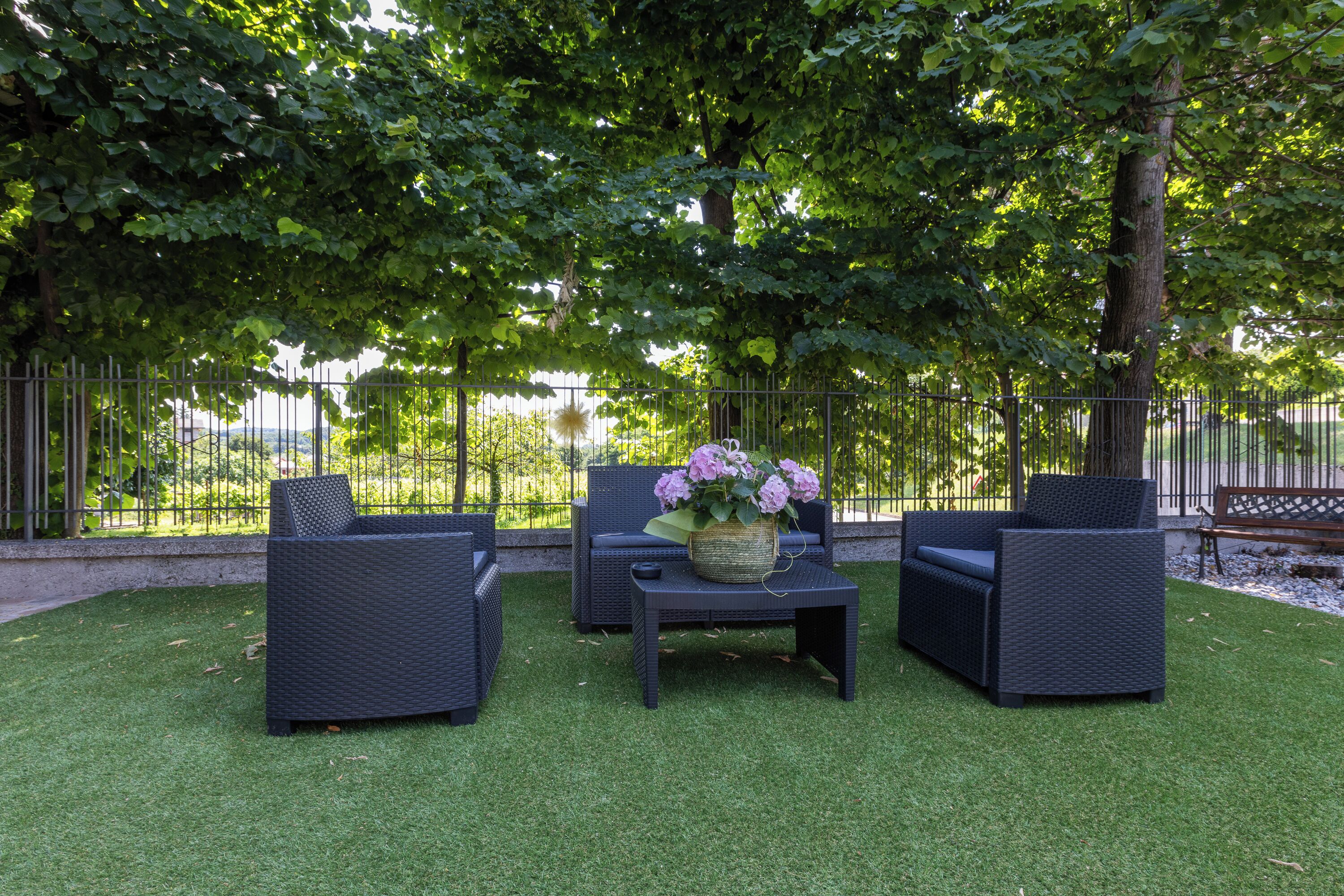 An outdoor seating area with wicker furniture and a table with a vase of flowers.