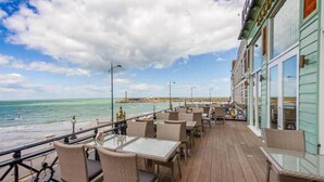 A deck with wicker furniture and glass tables overlooking the ocean. - Cosy Coach House Garden Apt by the Sea Res Parking (Broadstairs)