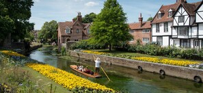 A canal with a rowboat, a person rowing, and traditional buildings on the banks. - Cosy Coach House Garden Apt by the Sea Res Parking (Broadstairs)