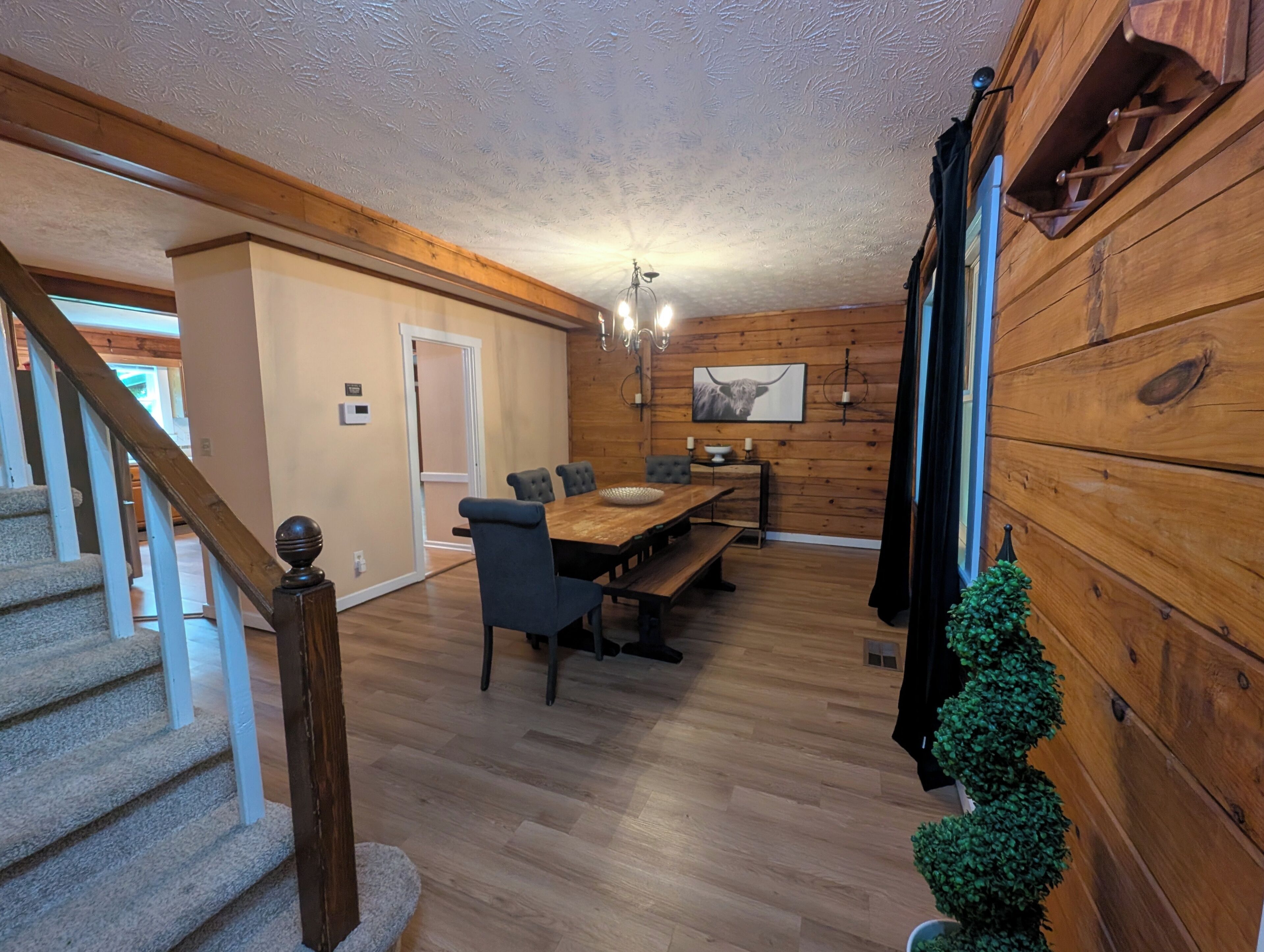 Interior de madera con comedor, escalera y una pequeña planta en maceta.