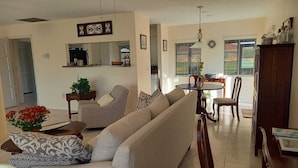 A living room with a sofa, armchair, coffee table, and dining area with chairs and a table. - Ferienvilla Bell Villa Bonita Springs (Bonita Springs)