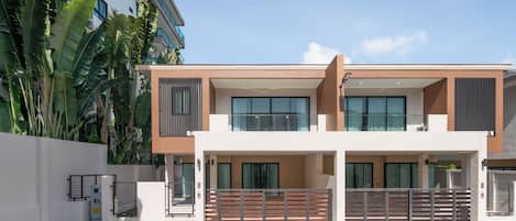 Un immeuble résidentiel moderne à deux étages, doté d’un toit plat, de grandes fenêtres et d’une entrée sécurisée par un portail.