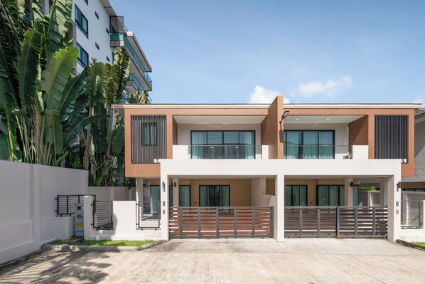 A modern two-story residential building with a flat roof, large windows, and a gated entrance. - Chao Wilai Residence | Naiyang Beach | HKT Airport (Sa Khu)