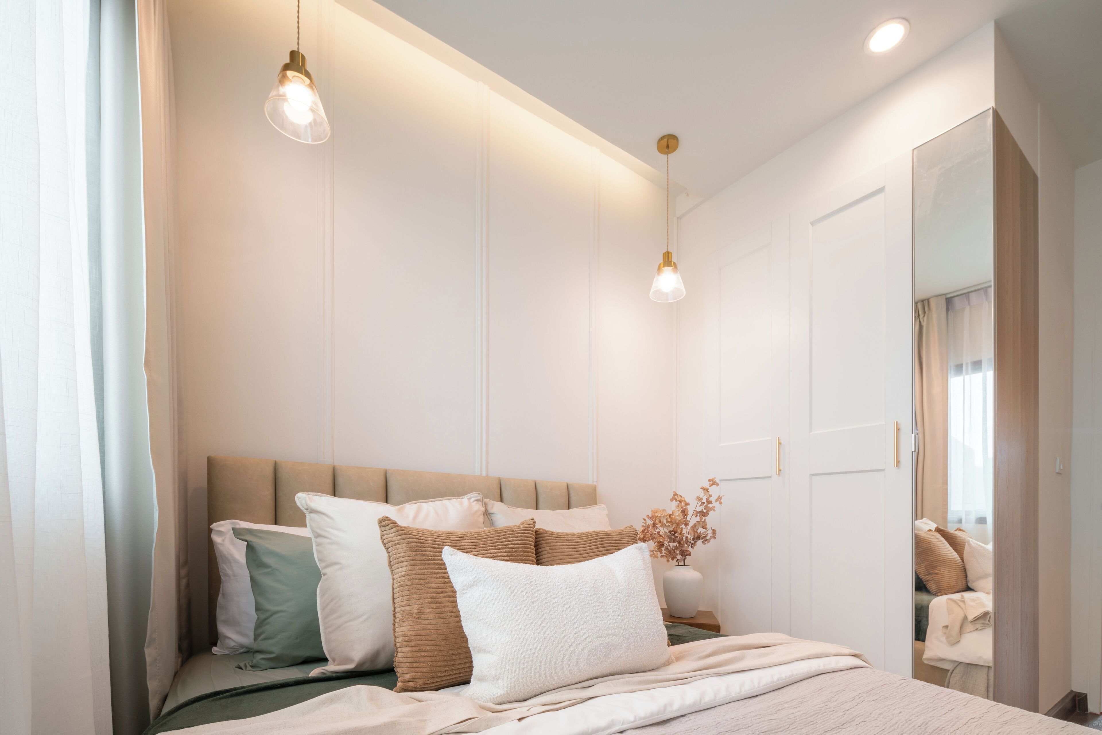 A modern bedroom with a bed, bedside tables, and a mirror.