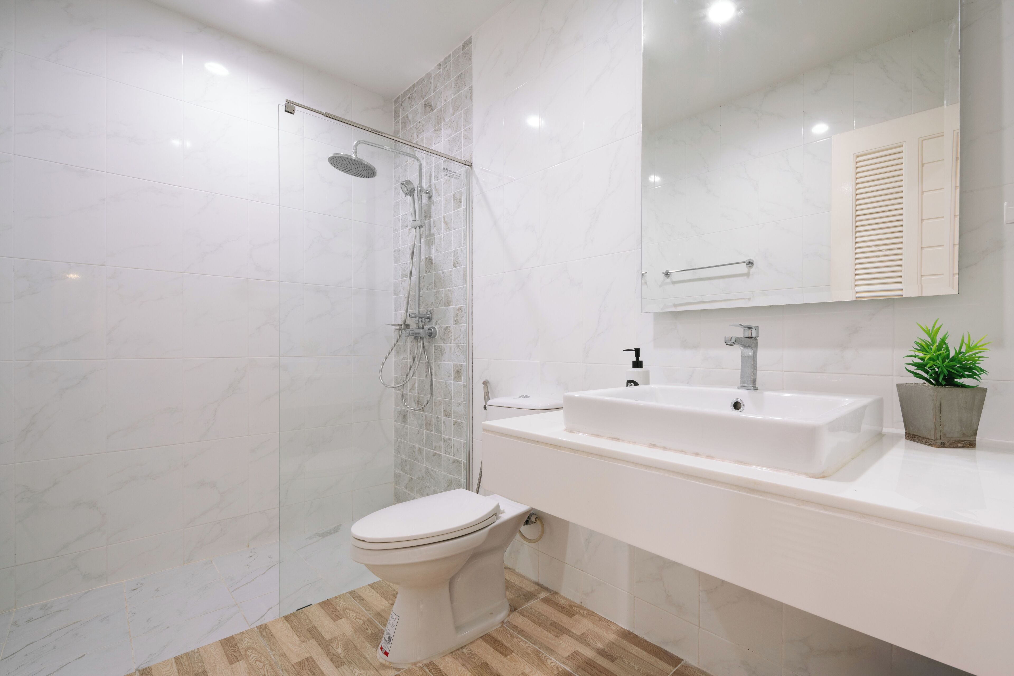 Een moderne badkamer met douche, toilet en wastafel.