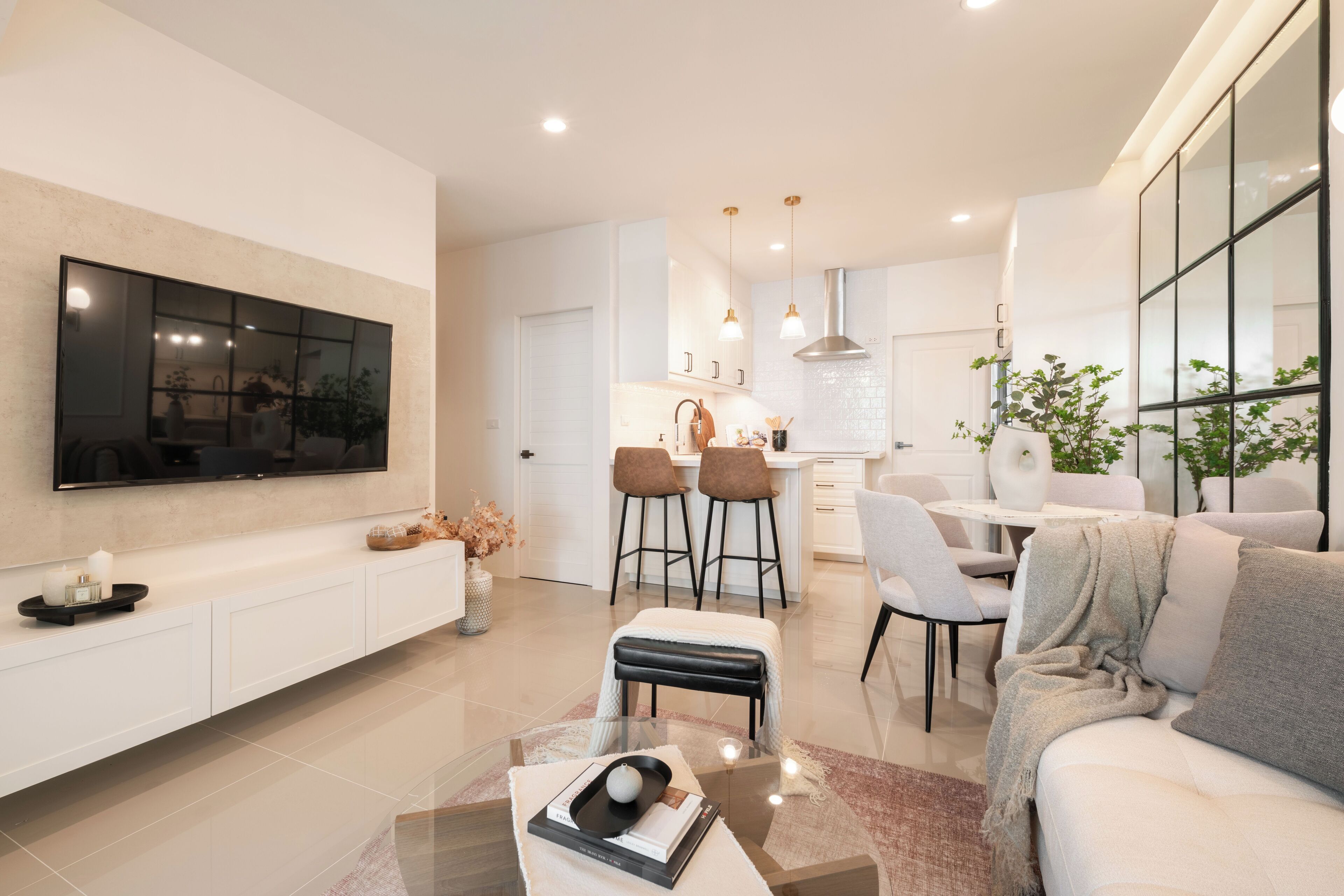 A modern kitchen with white cabinets, a dining area with a white table and chairs, and a living room with a sofa and a coffee table.