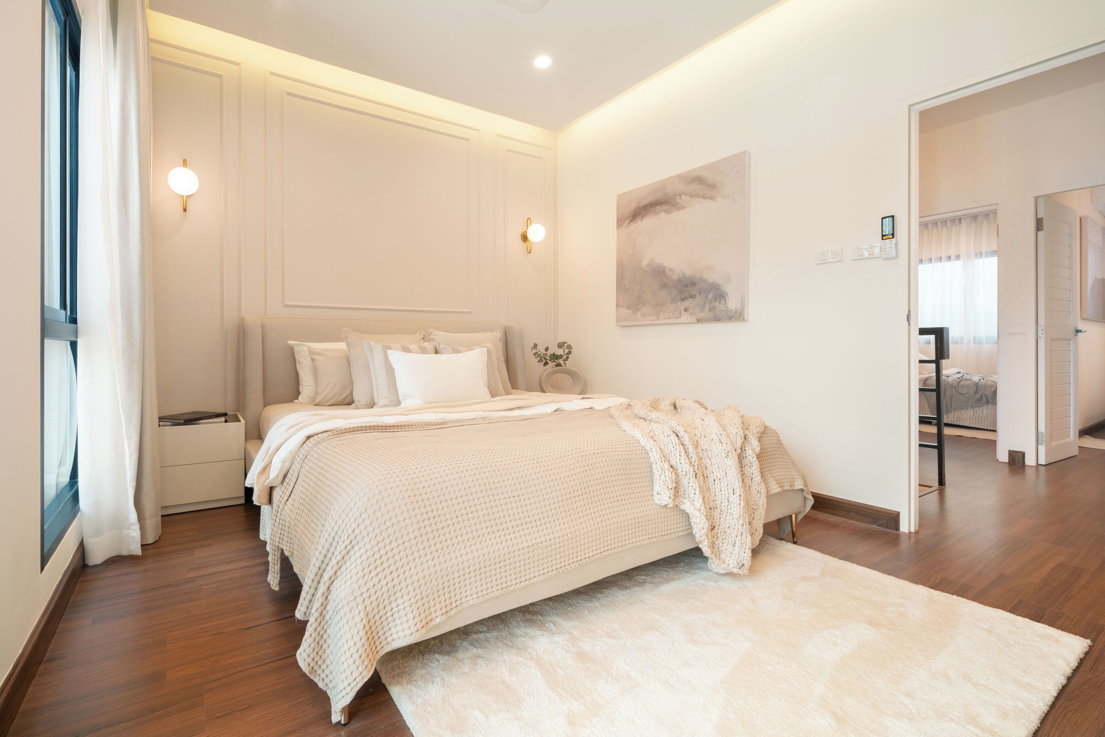 Ein Schlafzimmer mit einem großen Bett, einem Nachttisch, einer Wandlampe und einem Gemälde.