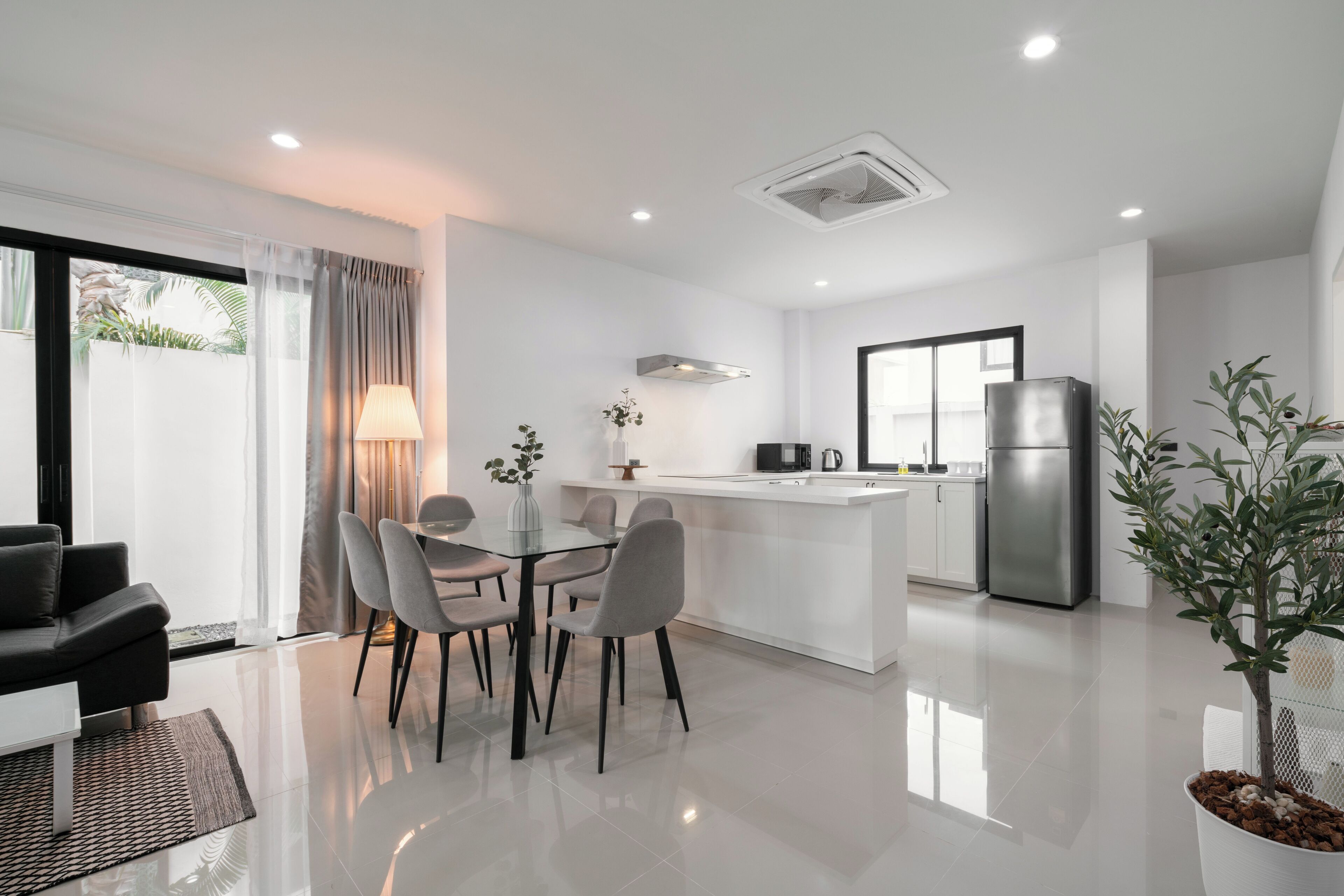 A modern kitchen with a central island, white cabinetry, and a stainless steel refrigerator.