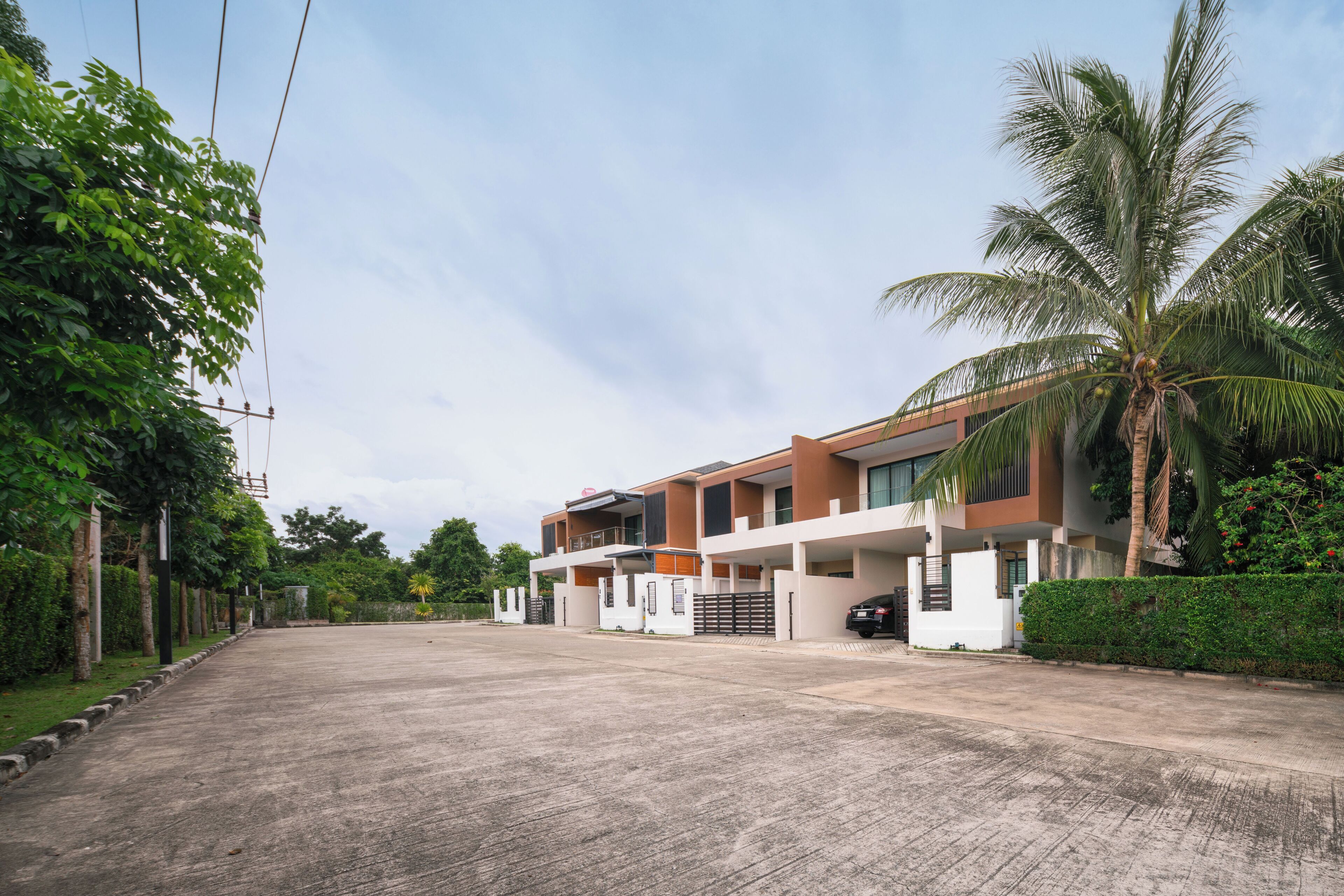 A modern two-story residential building with a flat roof, large windows, and a gated entrance.