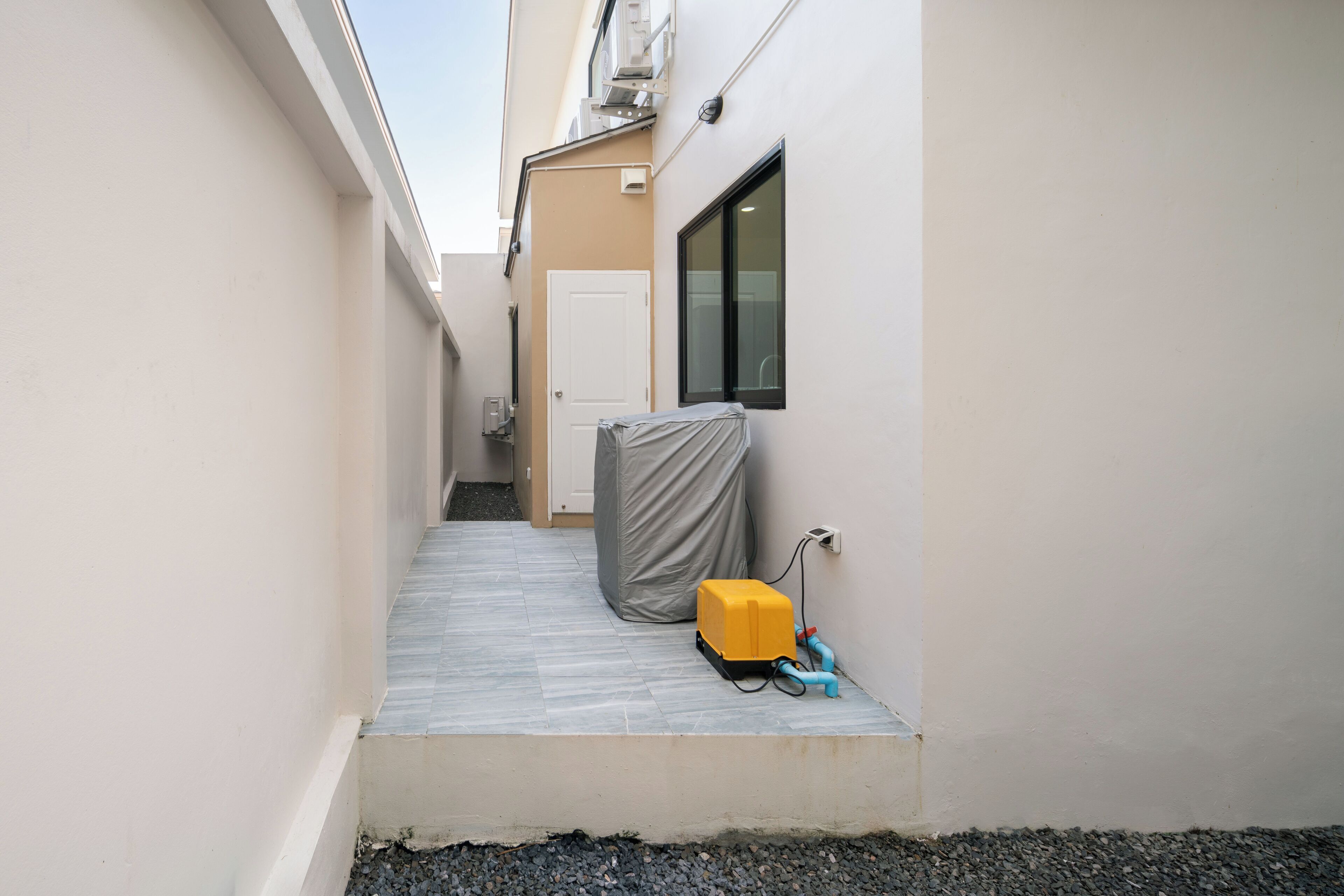 A narrow alleyway with a covered object and a yellow device on the ground.