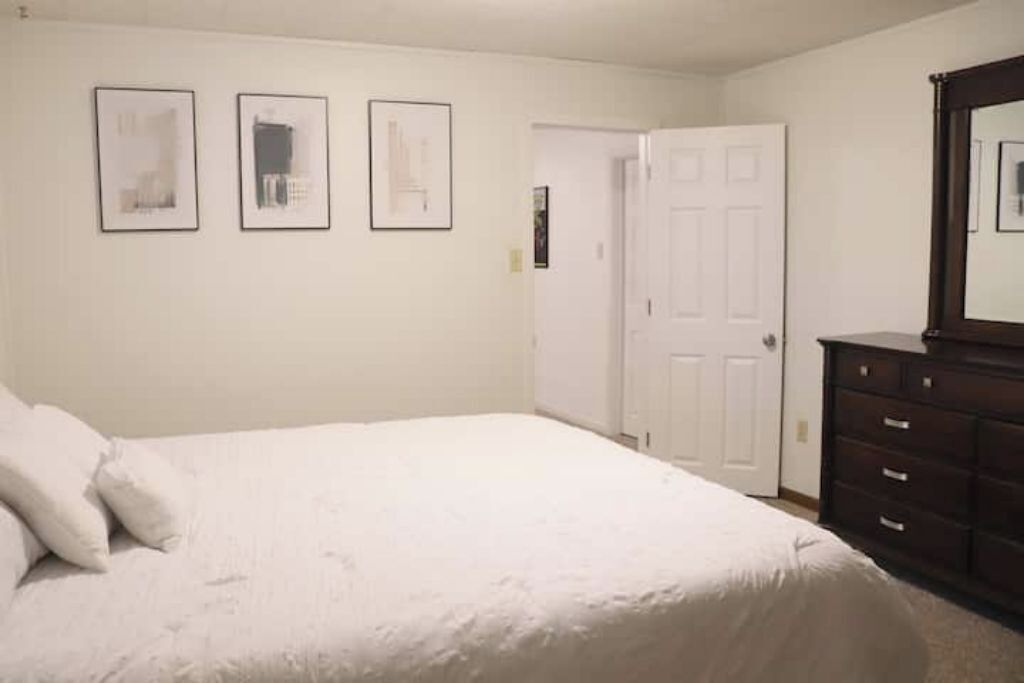 A bedroom with a bed, a dresser, and three framed pictures on the wall.