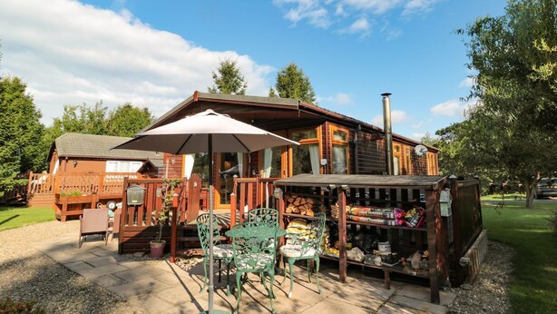 Une cabane en bois dotée d’un patio, de mobilier d’extérieur et d’une petite boutique.