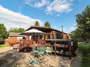 Una cabaña de madera con un patio, muebles de exterior y una pequeña tienda.