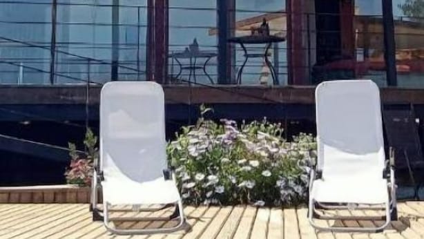 Un edificio moderno de dos pisos con área de piscina, que incluye sillones de descanso y vista a la piscina.