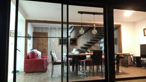Un interior moderno con una zona de comedor, un sofá rojo y una escalera.