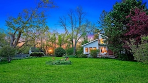 A house with a well-maintained lawn and a porch with outdoor seating. - Cozy Cottage by Lake Simcoe | Private Dock & Kayaks Included (Brechin)