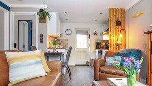 Una sala de estar moderna con sofás de cuero, una mesa de centro y un comedor con una cocina al fondo.