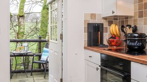 Una cocina con encimera de madera, estufa y ventana con vistas a un jardín.