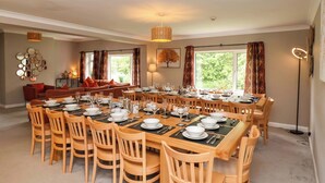 A dining area with a large round table set for a meal, surrounded by wooden chairs. - Hazelgarth House (Filey)