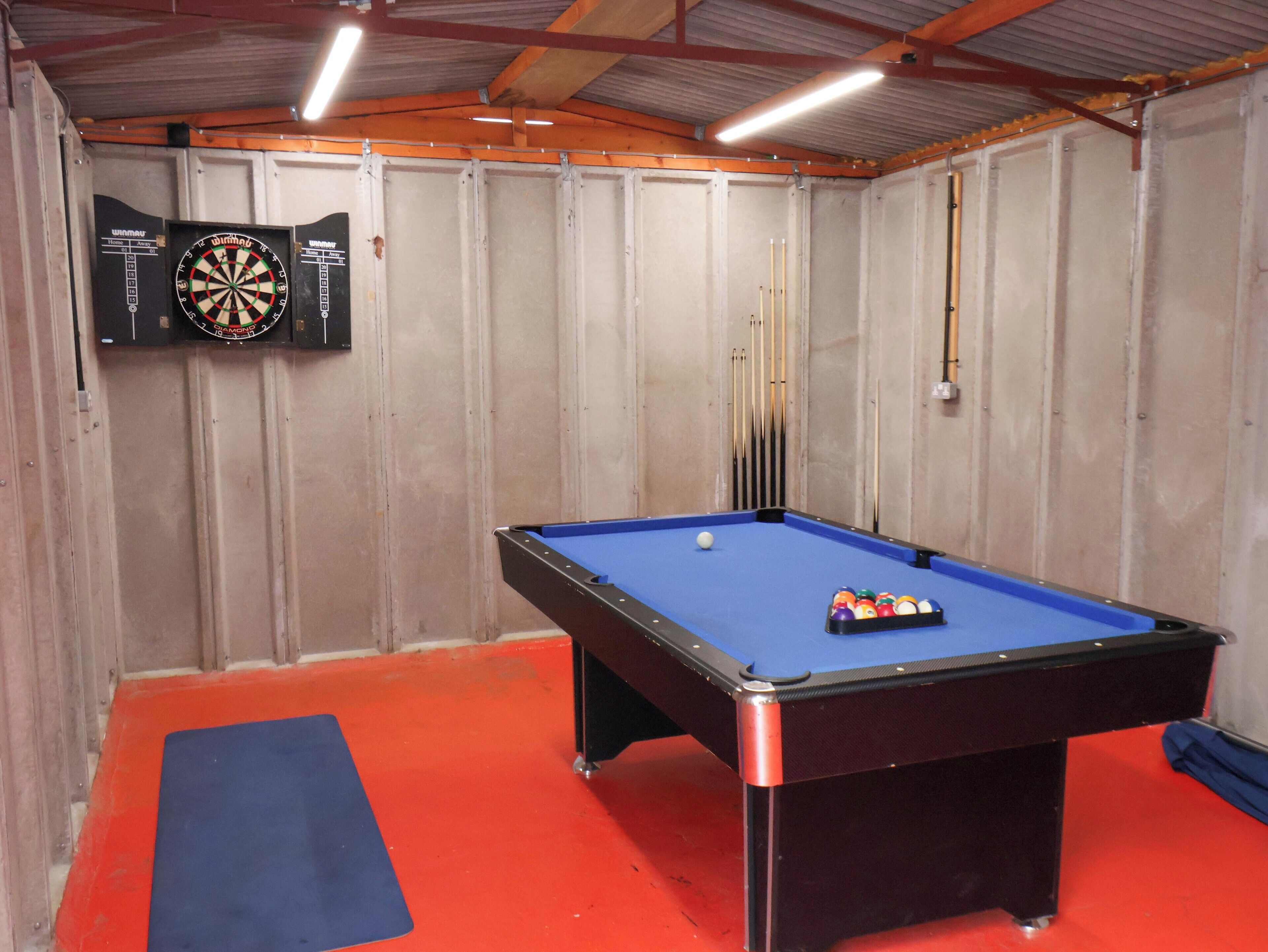 A pool table with a blue felt surface, surrounded by a red floor.