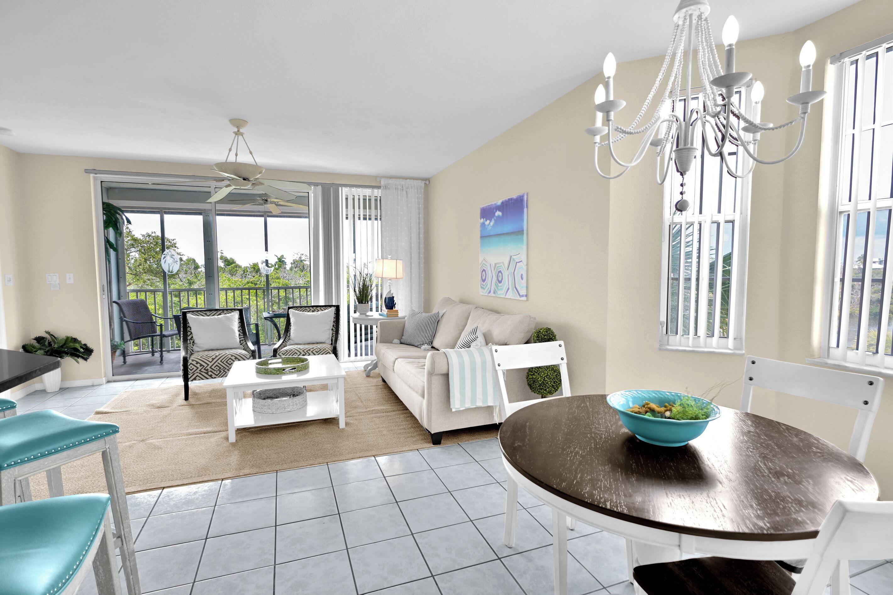 A modern living room with a dining area, large windows, and a ceiling fan.