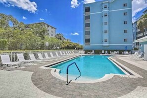 A swimming pool with lounge chairs and a building in the background. - Beach Access | Lanai | Kayak & Boat Rentals (Fort Myers Beach)