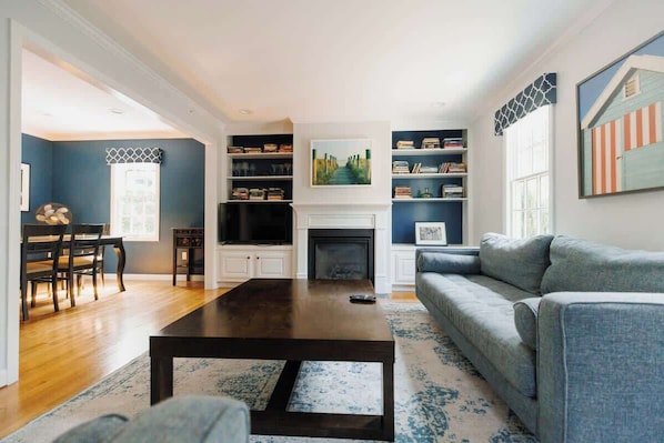 A living room with a fireplace, a sofa, a coffee table, and bookshelves.
