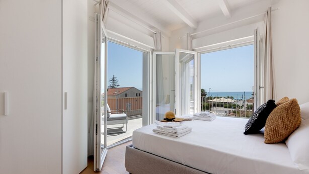 Un dormitorio con cama, ventana y vista al mar.