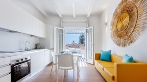 Una cocina moderna con armarios blancos, un horno de acero inoxidable y una zona de comedor con mesa y sillas.