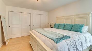 Une chambre à coucher avec un lit blanc, des oreillers turquoise et une tête de lit blanche.