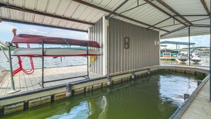Ein überdachter Bootsstellplatz mit Schwimmbad, angestaute Booten und Blick auf das Wasser.