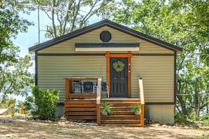 A small, single-story building with a front porch, a door with a wreath, and a small window. - Private Hot Tub & Dock: Lakefront Grove Retreat! (Grove)