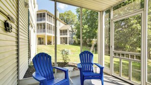 A covered porch with two blue Adirondack chairs and a white table. - Branson Condo w/ Screened Patio, Pool Access (Branson)