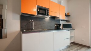 Eine moderne Küche mit weißen Schränken, einer schwarzen Mikrowelle und einer Kaffeemaschine.