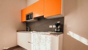 Una cocina con armarios blancos, una cafetera negra y un microondas.