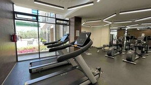 A gym with treadmills, weight machines, and a large window providing natural light. - Loft Estudio Cdmx Alberca y Gym / Smart Penthouse (Ciudad de México)